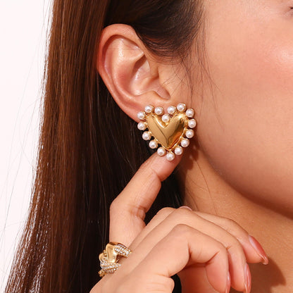 Heart-shaped gold earring with pearls worn by a person