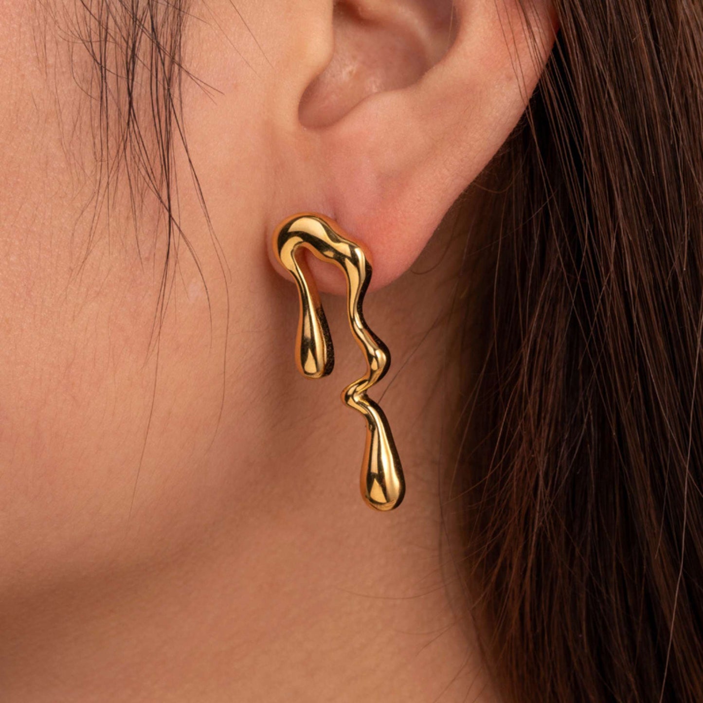 Gold geometric earring worn on an ear with a close-up view