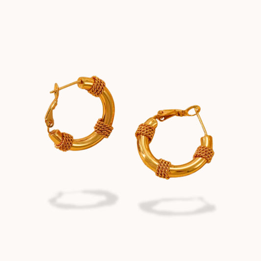 Pair of gold hoop earrings with rope tied design on a white background