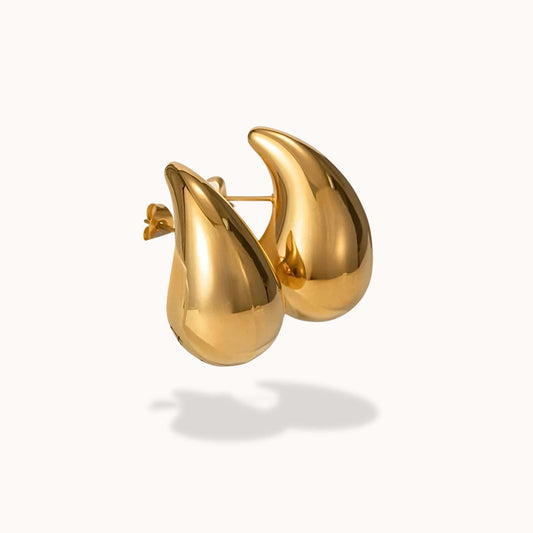 Gold tear drop earrings on a white background