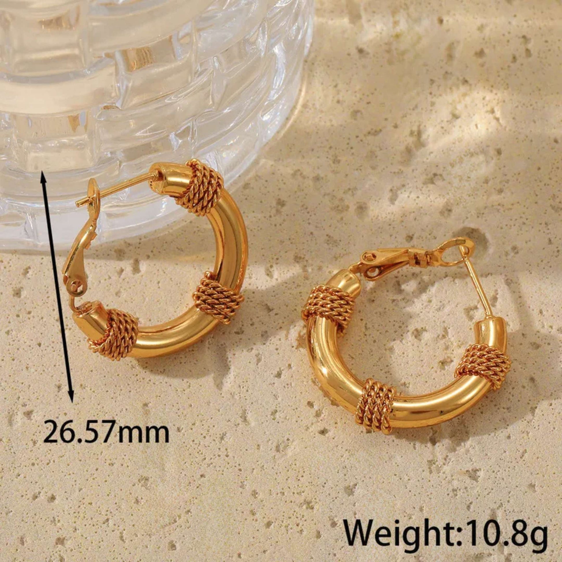 Gold hoop earrings on a textured surface with measurements and weight displayed.