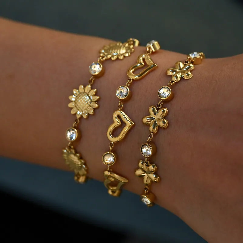 Gold bracelet with various charms on a wrist against a dark background