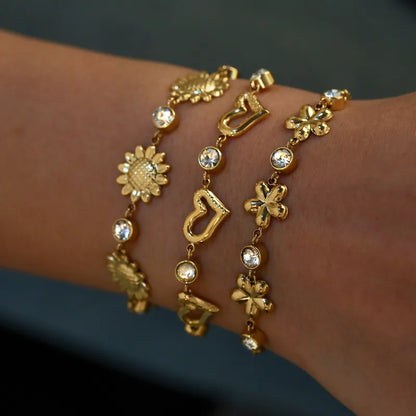 Gold bracelet with various charms on a wrist against a dark background