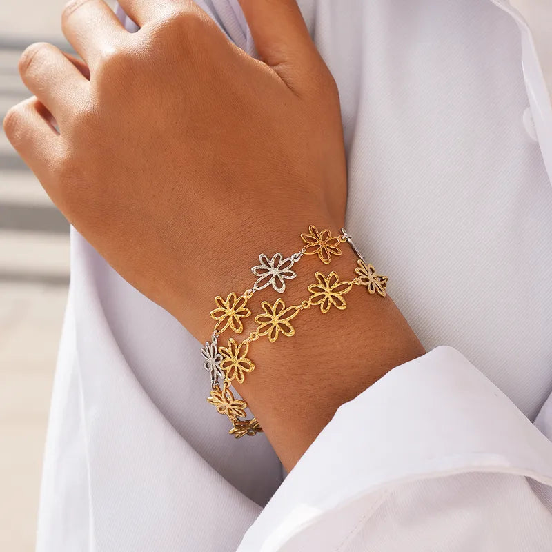 Gold and silver floral bracelet on a person's wrist with a white background