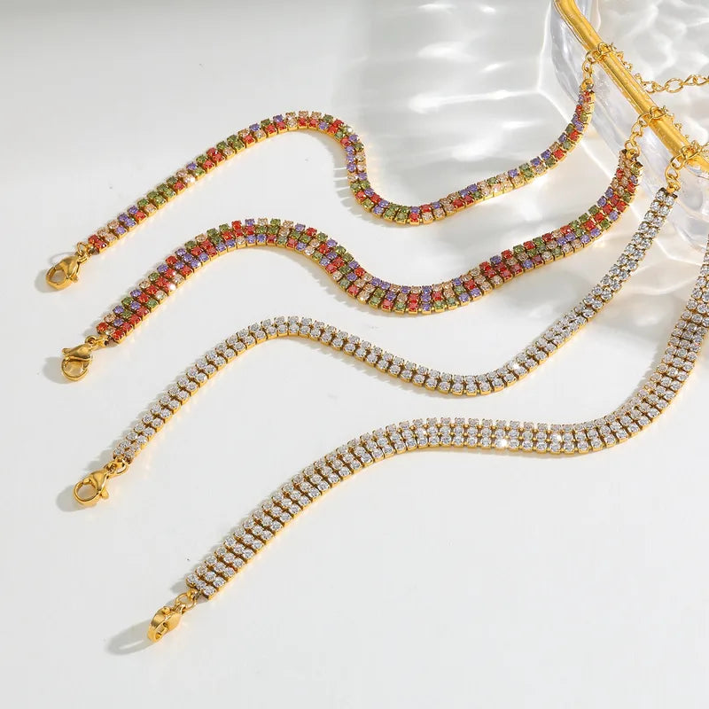 Three gold bracelets with different gemstone designs on a white surface