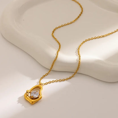 Gold necklace with a heart-shaped pendant on a light background