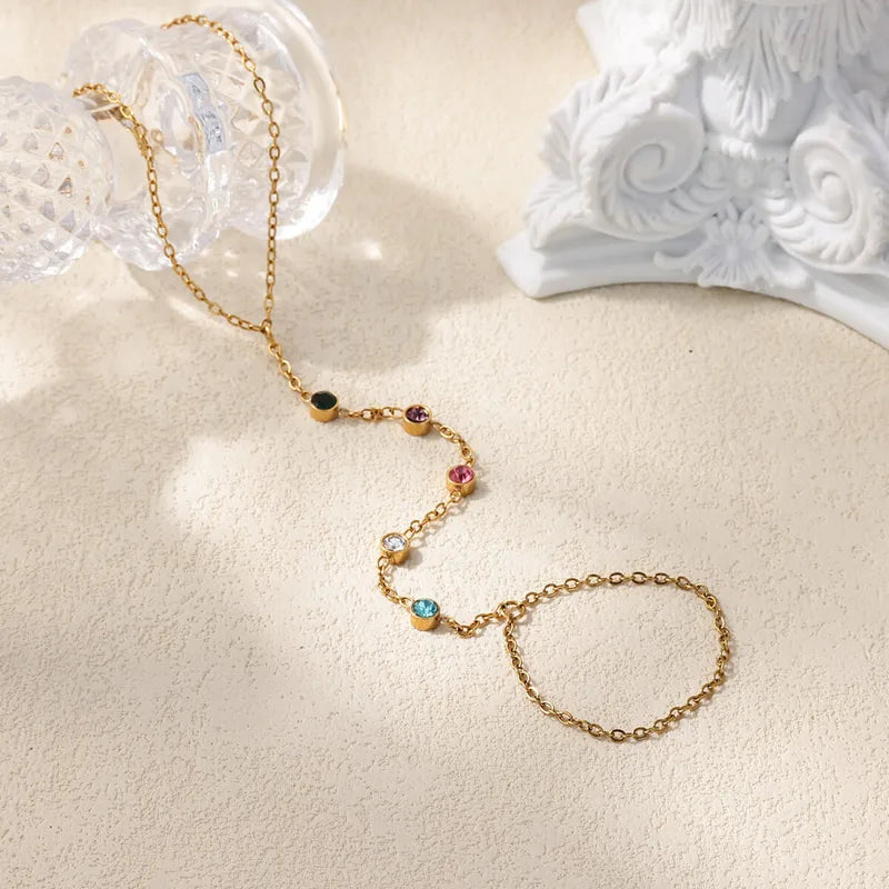 Gold bracelet with colorful beads on a beige surface