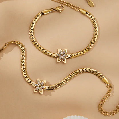 Gold chain bracelet with floral clasp on a beige background
