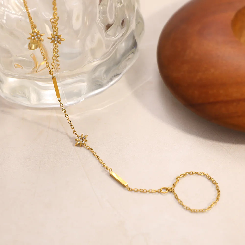 Gold necklace with star-shaped pendant on a white surface