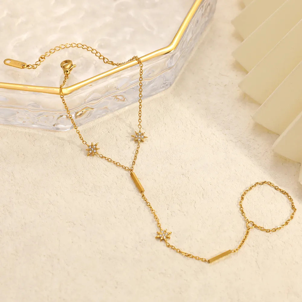 Gold necklace with star-shaped pendants on a light beige surface