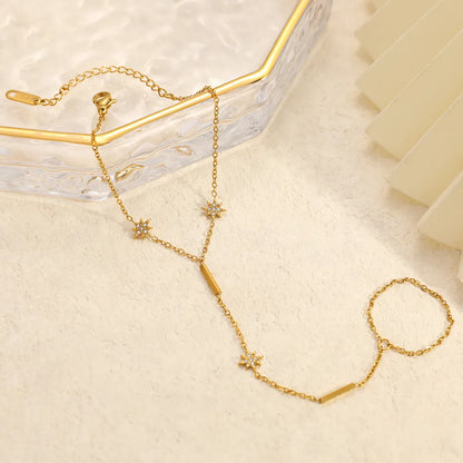 Gold necklace with star-shaped pendants on a light beige surface