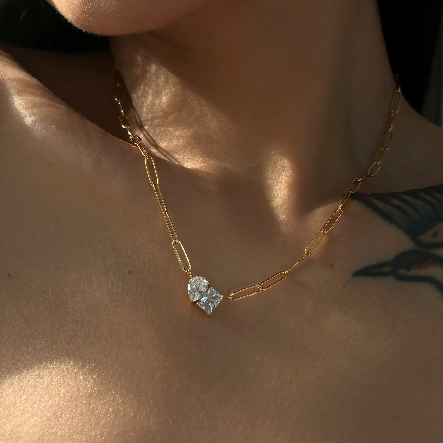 Gold necklace with a blue gemstone on a person's neck
