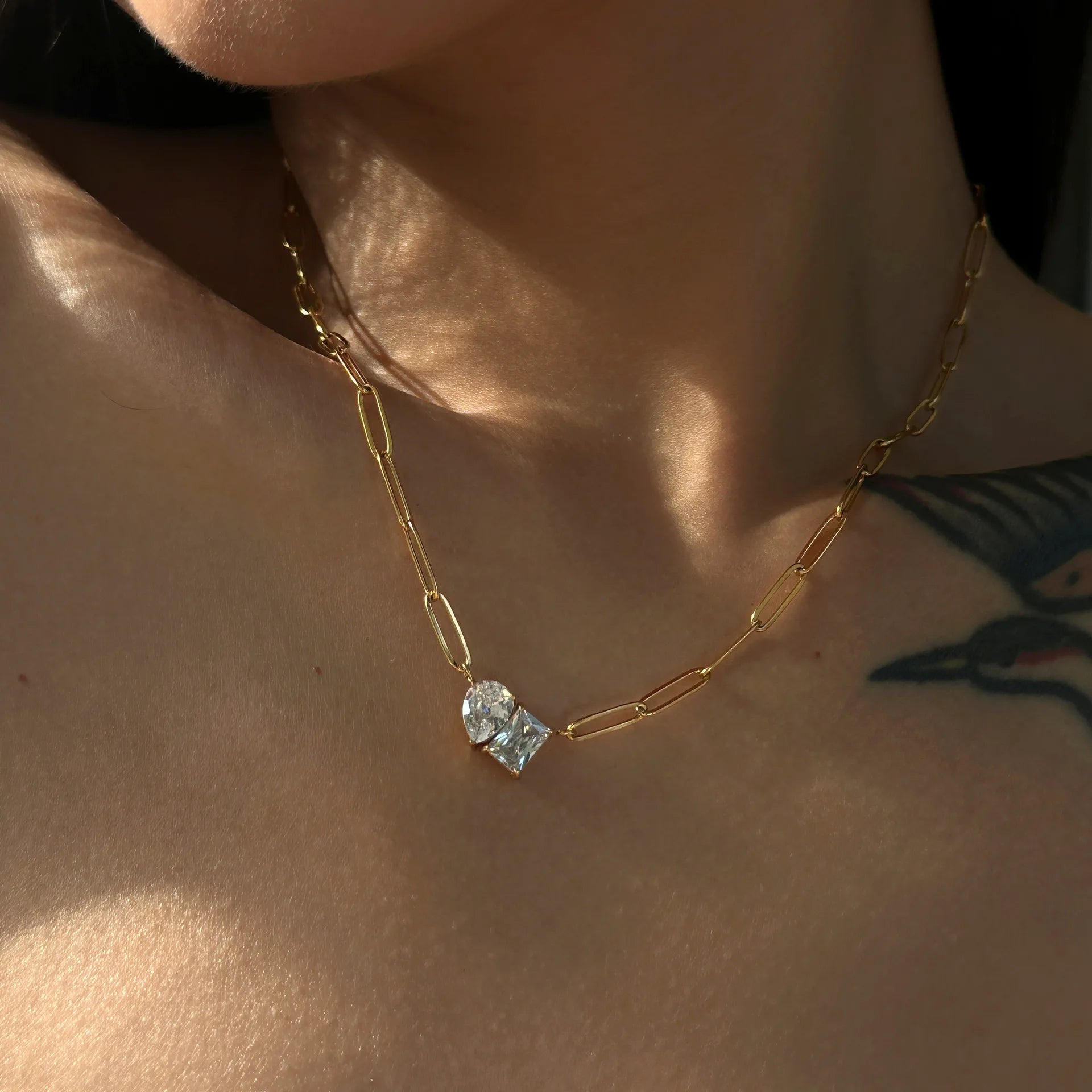 Gold necklace with a blue gemstone on a person's neck