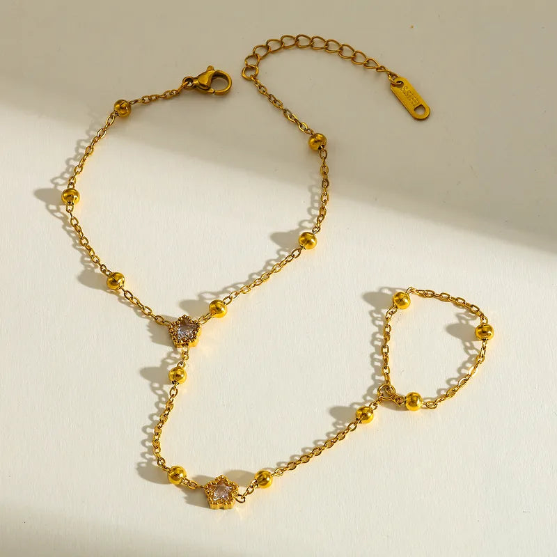 Gold chain handchain with small diamond-like pendants on a beige background