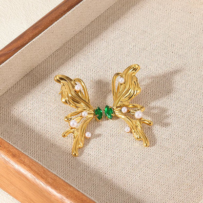 Gold earrings with green and pearl accents on a beige fabric background