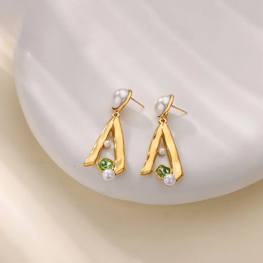 Gold earrings with green gemstones and pearls on a white background