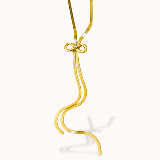 Gold necklace with a bow-shaped pendant on a white background