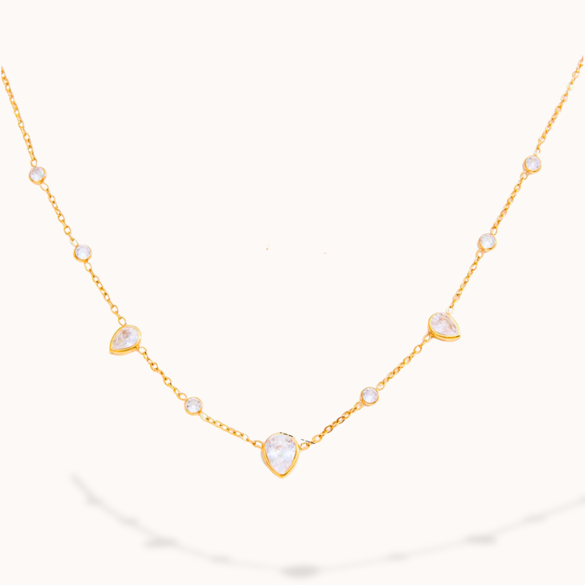 Gold necklace with teardrop-shaped pendants on white background