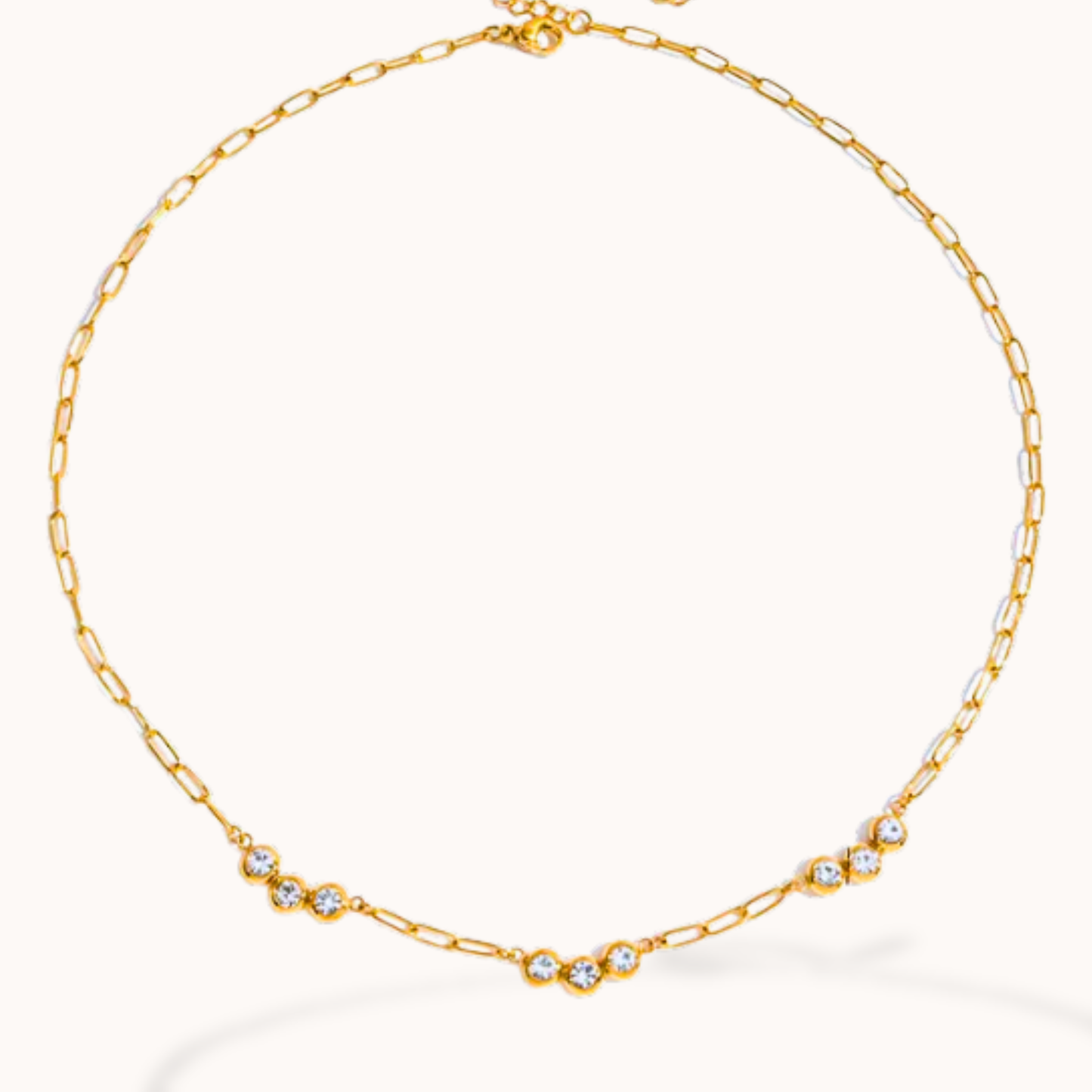 Gold chain necklace with small crystals on a white background