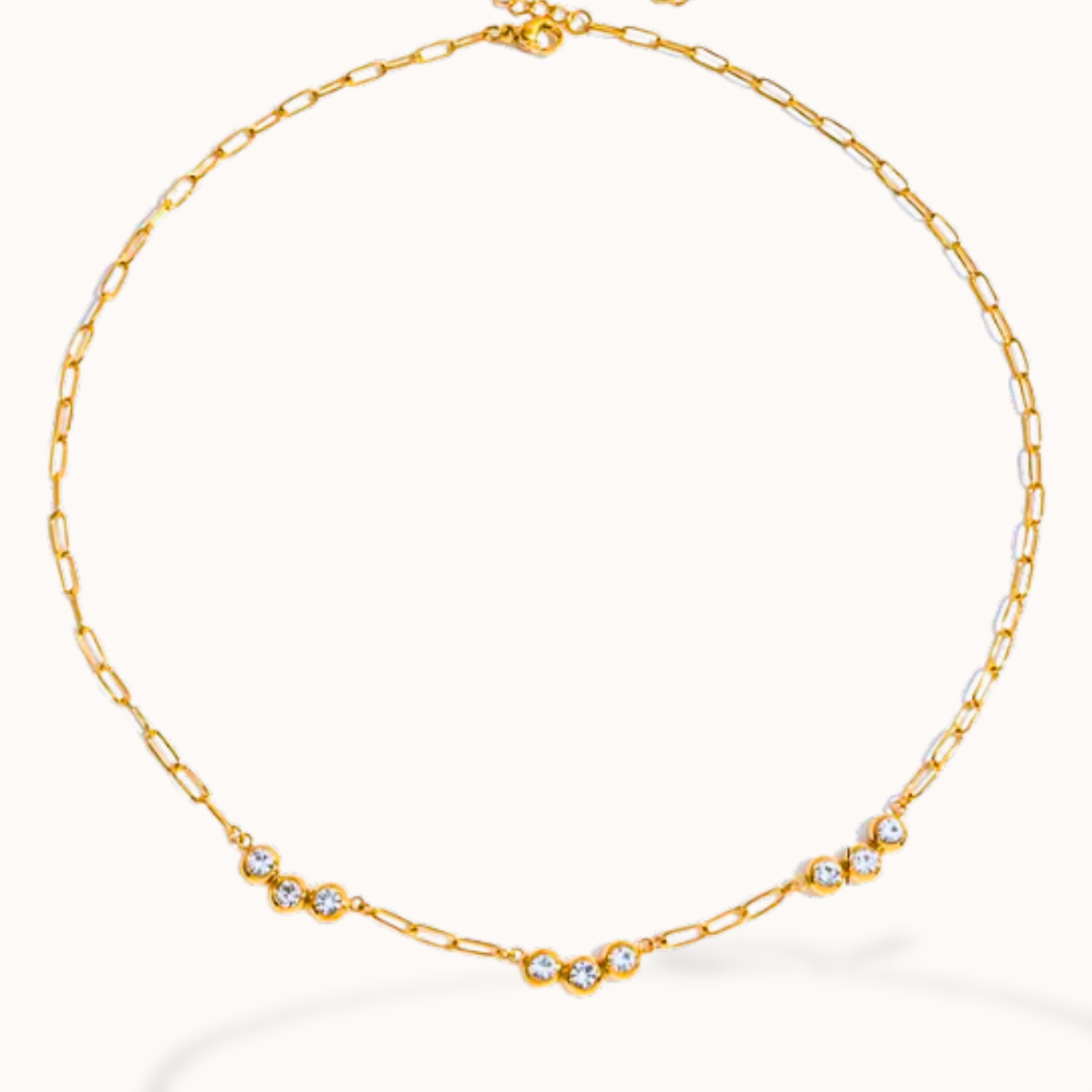 Gold chain necklace with small crystals on a white background