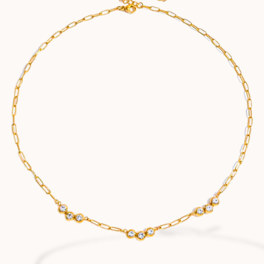 Gold chain necklace with small crystals on a white background