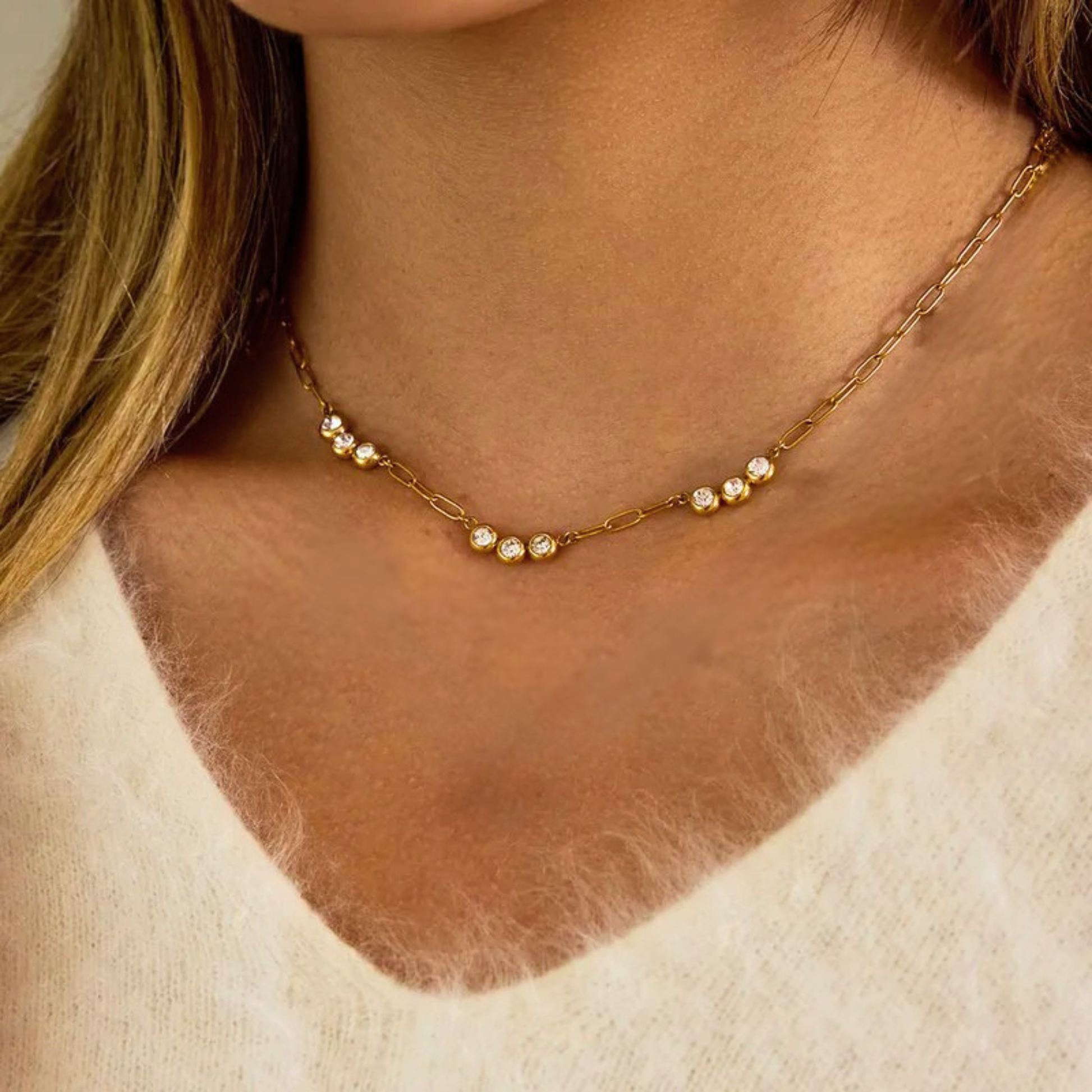 Gold chain necklace with small crystals on a person