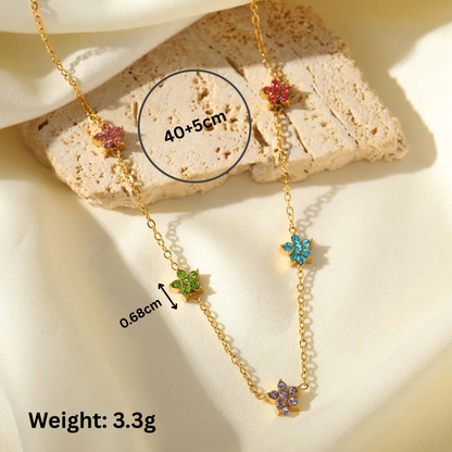 Gold necklace with colorful flower pendants on a stone surface, showing measurements and weight.