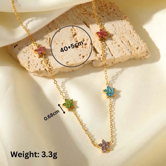 Gold necklace with colorful flower pendants on a stone surface, showing measurements and weight.