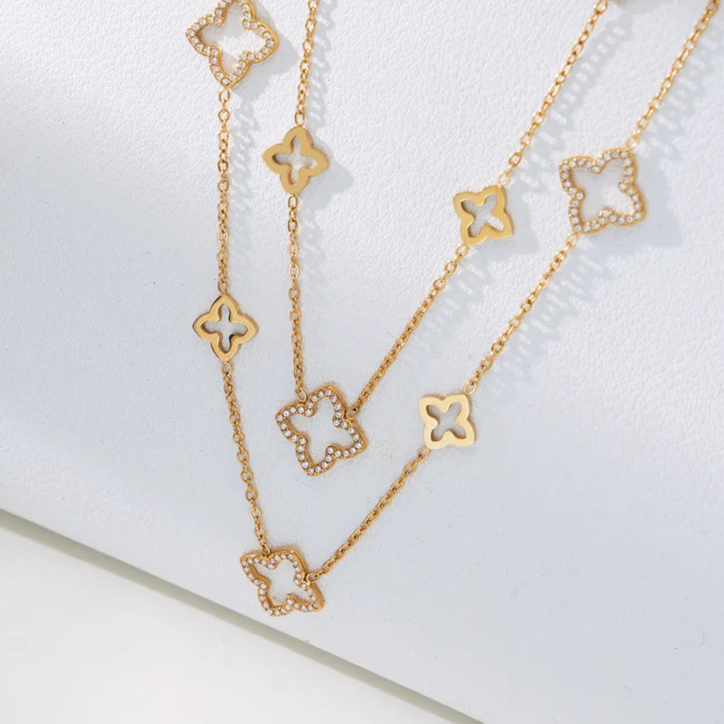 Gold necklace with clover-shaped pendants on a white background
