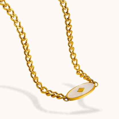 Gold chain necklace with a white pendant on a white background