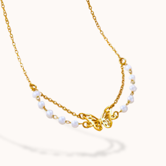 Necklace with gold butterfly charm and pearl beads on a white background