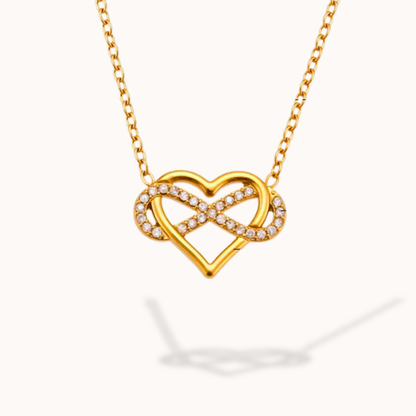 Gold necklace with a heart and infinity symbol pendant on a white background