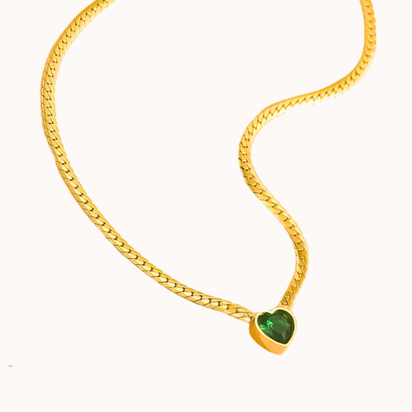 Gold chain necklace with a green gemstone pendant on a white background