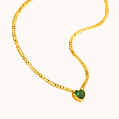 Gold chain necklace with a green gemstone pendant on a white background