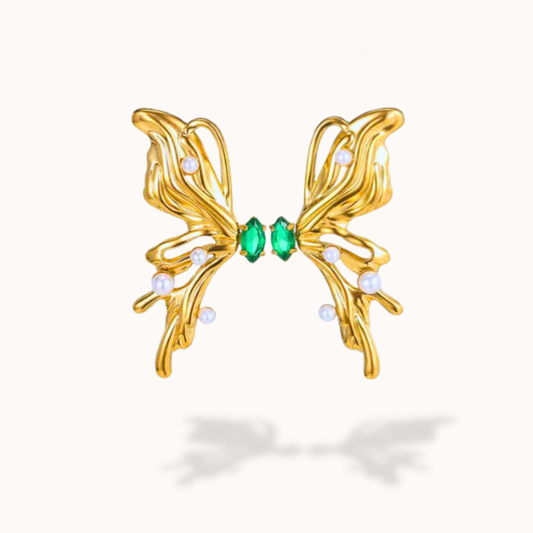 Gold butterfly-shaped earring with green gemstones on a white background