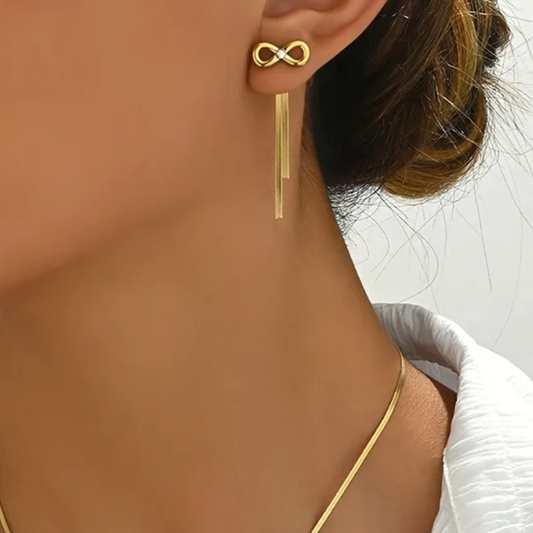 Gold earring with infinity symbol worn by a person