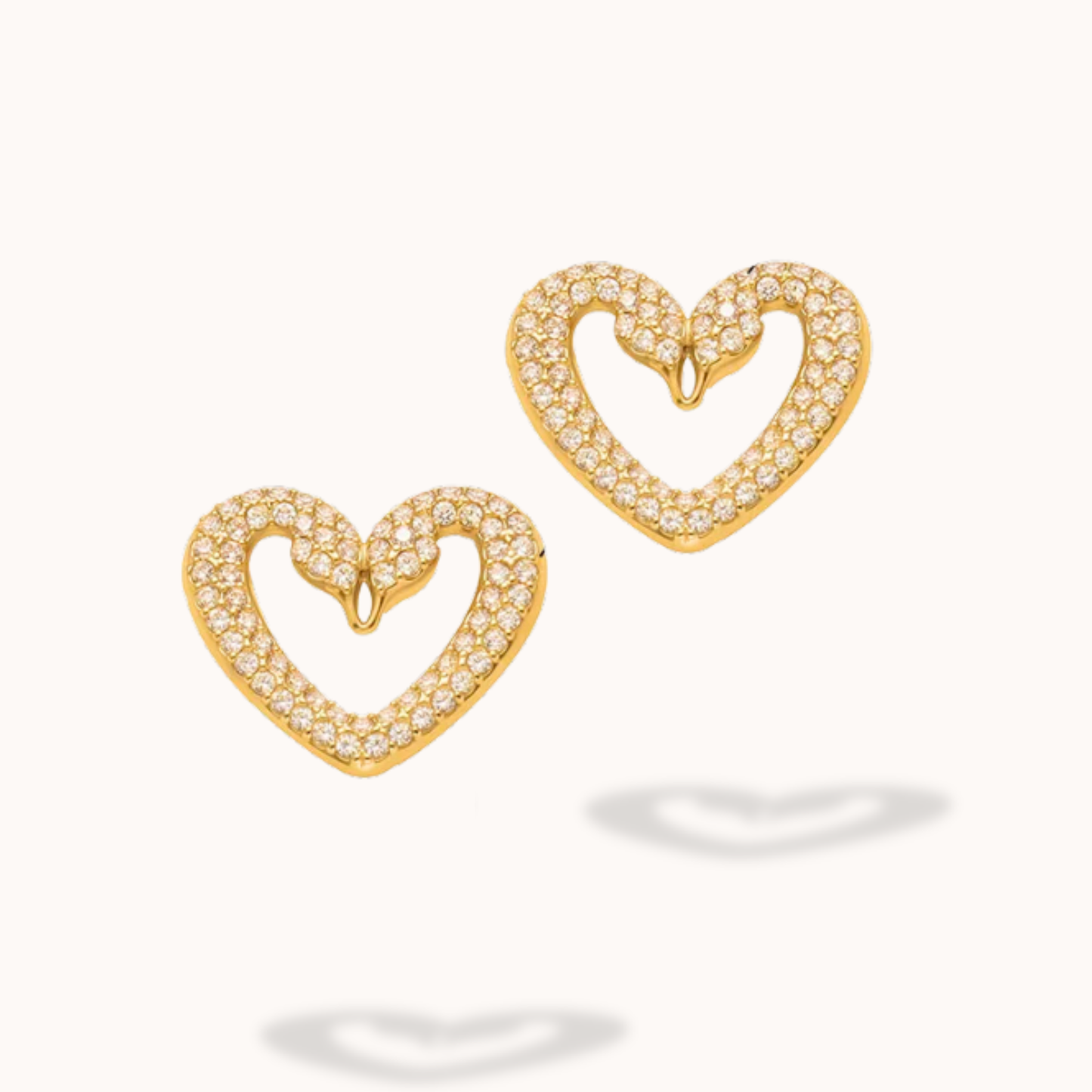 Gold heart-shaped earrings with clear stones on a white background