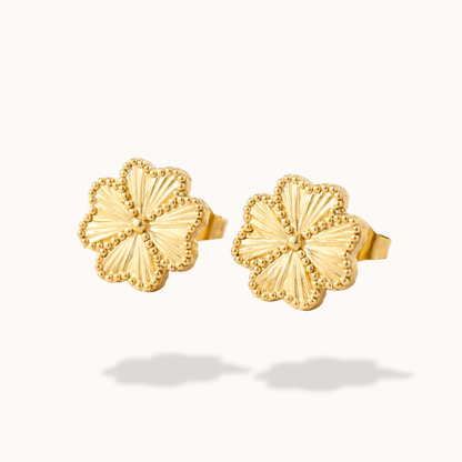 Pair of gold floral earrings on a white background