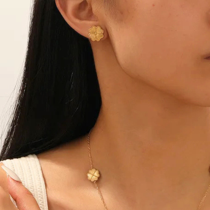 Close-up of a person wearing gold floral earrings and a matching necklace.