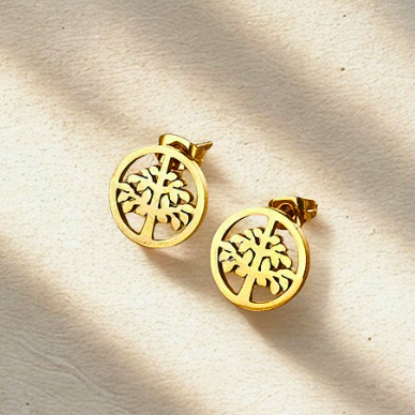 Gold tree-shaped earrings on a beige background
