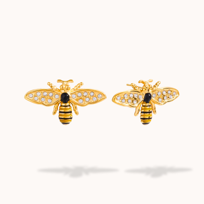 Gold bee-shaped earrings with black and clear gemstones on a white background