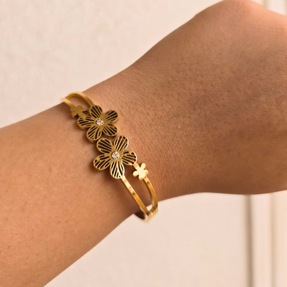 Gold floral bracelet on a wrist against a neutral background