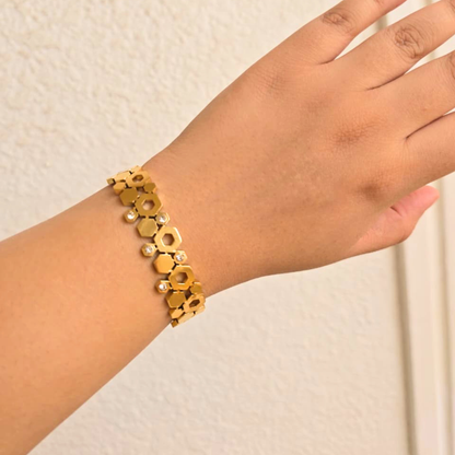 Gold bracelet on a wrist against a neutral background