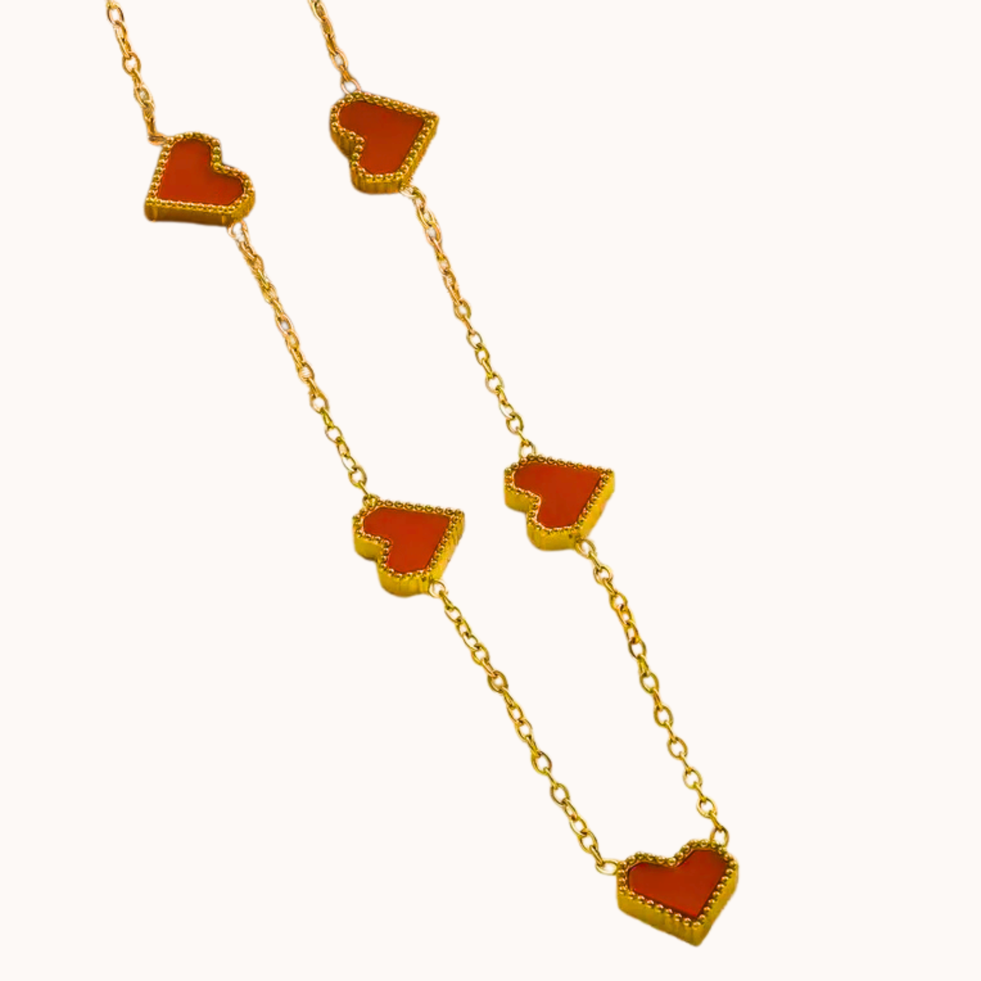 Gold necklace with red heart pendants on a white background