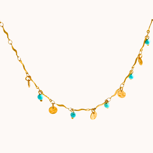 Gold necklace with turquoise and yellow beads on a white background