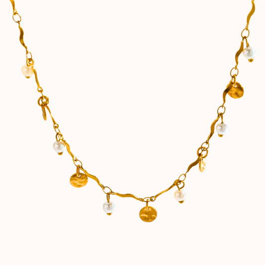 Gold necklace with pearl and gold disc beads on a white background