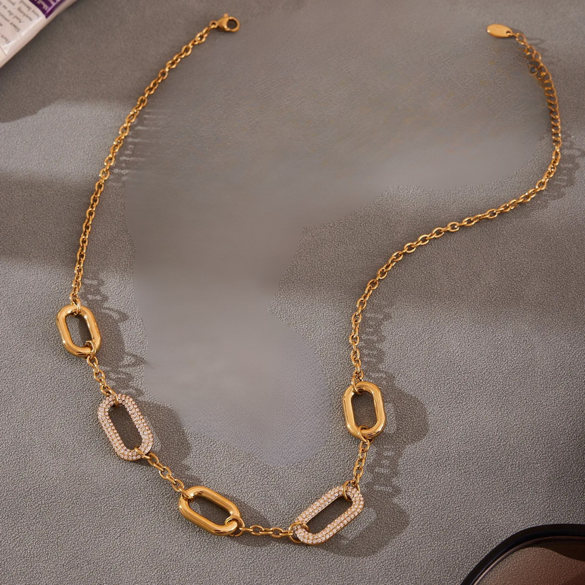 Gold chain necklace on a gray surface