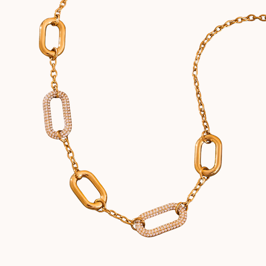 Gold chain necklace with diamond accents on a white background