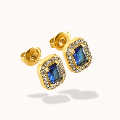 Gold earrings with blue gemstones on a white background