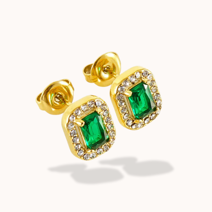 Gold earrings with green gemstones on a white background